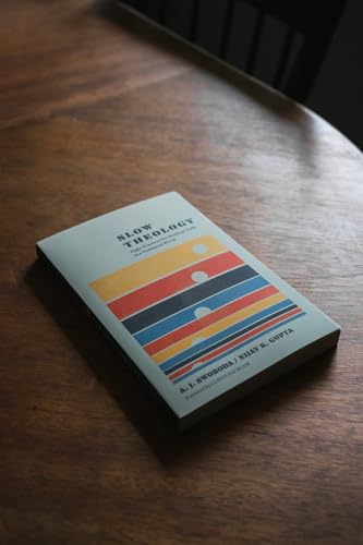 Book cover with colorful stripes titled “Slow Theology” on a wood surface.