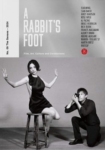 Magazine cover featuring a woman posing on a stool while a man photographs her.