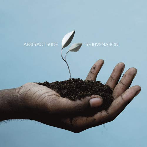 A hand holds a mound of soil with a small silver plant sprout growing out.