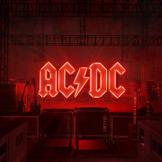 "AC/DC logo in red neon lights, surrounded by guitars and stage equipment."