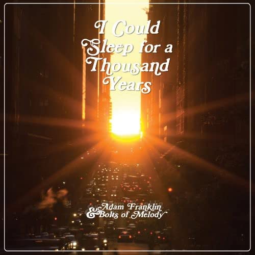 Vinyl record cover with golden text on a dark, city-street background.