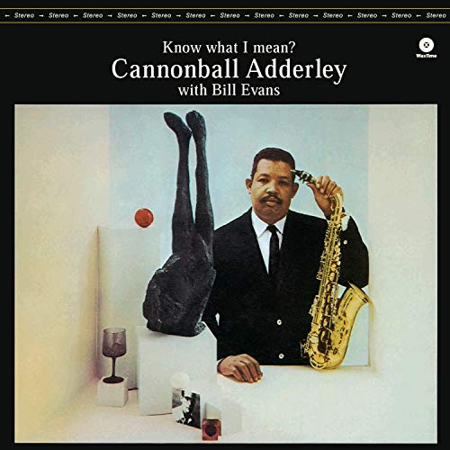 Cannonball Adderley in a suit holding a saxophone next to an abstract sculpture.