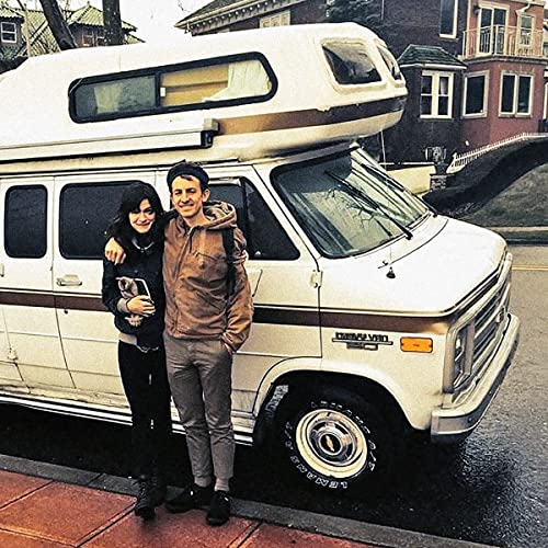 Adrianne Lenker and Buck Meek stand beside a vintage camper van.