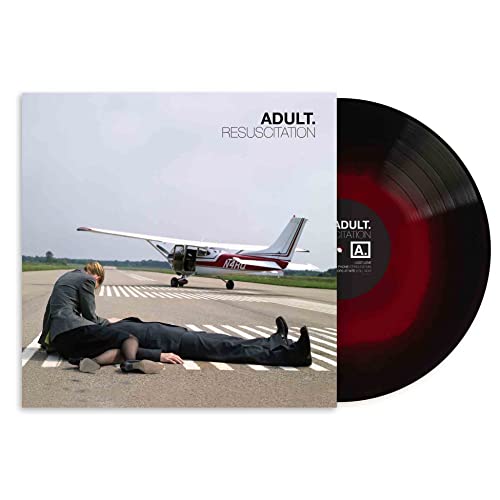 Album cover showing two people on a runway with a plane and red-black vinyl.