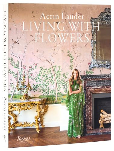 Aerin Lauder stands in a room with floral wallpaper, a gold console, and fireplace.