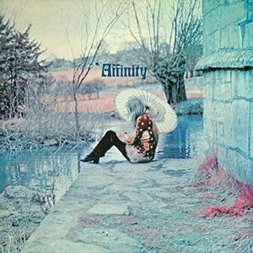 A person with a parasol sits by a stream on the Affinity album cover.