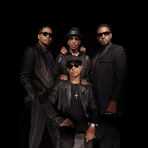 Four men in dark clothing and sunglasses, posing for a portrait.