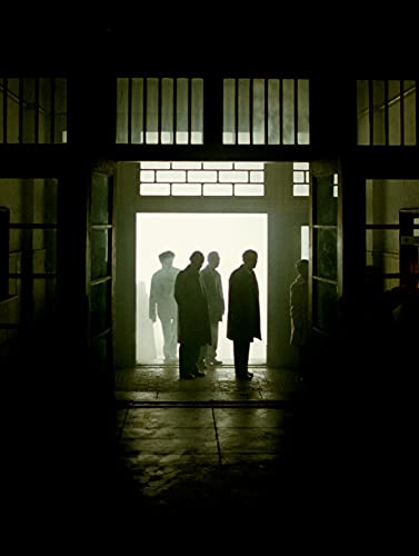 Silhouetted figures stand in a brightly lit doorway, dark surroundings.
