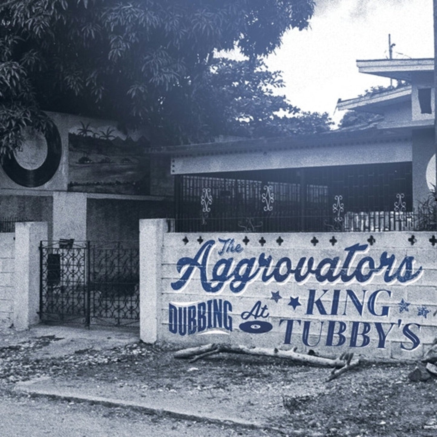 A blue-toned photo of a wall with The Aggrovators Dubbing At King Tubbys text.
