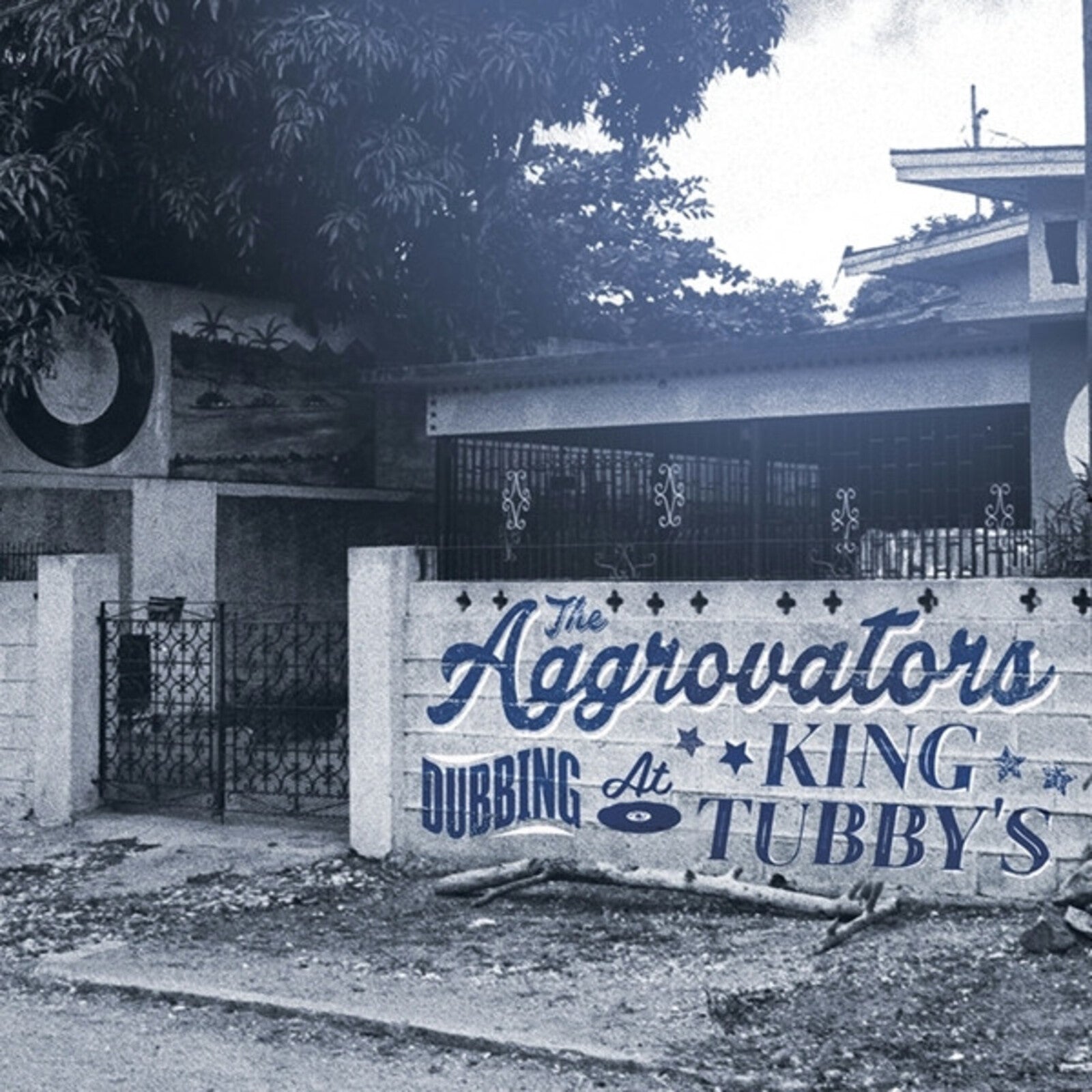 A blue-toned photo of a wall with The Aggrovators Dubbing At King Tubbys text.