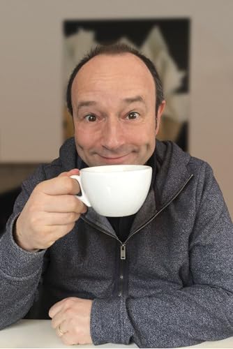 Man smiling and holding a white teacup, looking at the viewer.