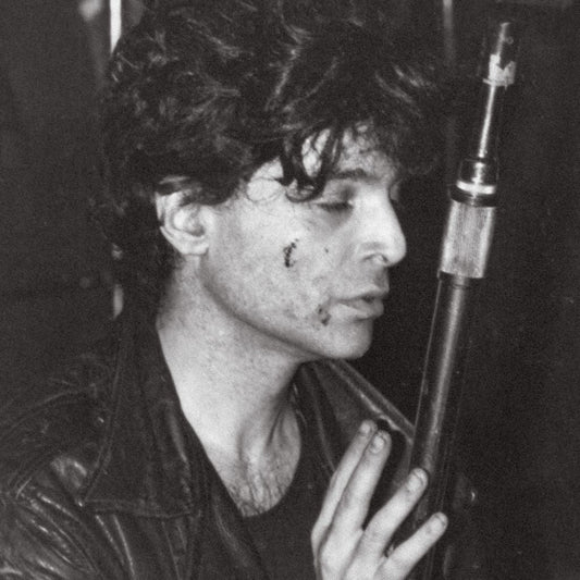 Black and white portrait of Alan Vega with a microphone, mid-performance.