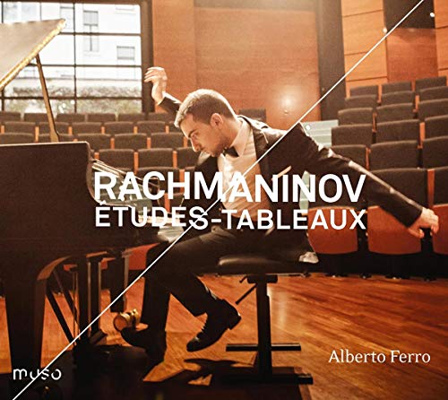 Pianist Alberto Ferro sits at a grand piano, wearing a tuxedo, in an empty auditorium.