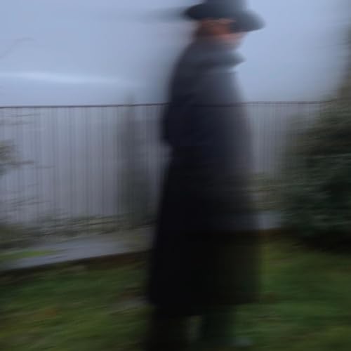Blurred image of a person in a hat and dark clothing.