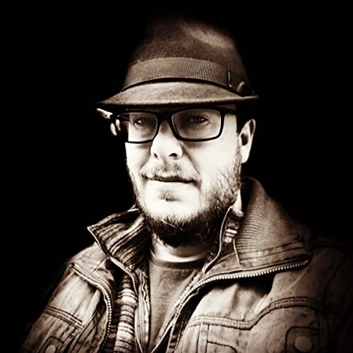 Sepia-toned portrait of a man with a beard, wearing a hat and glasses.