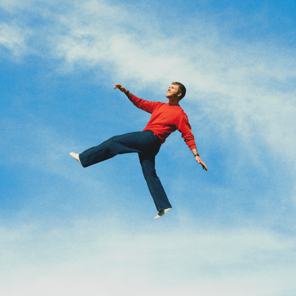Man in red sweater and jeans appears to be floating in a blue sky.