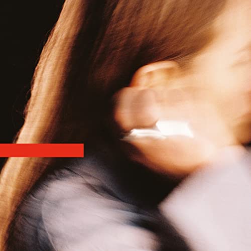 Close-up of a person with long hair, and a red horizontal stripe.