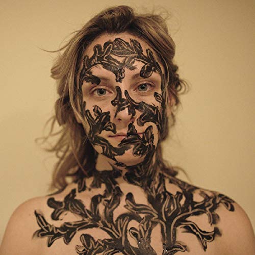 Woman with wavy brown hair and black floral body paint on her face and shoulders.