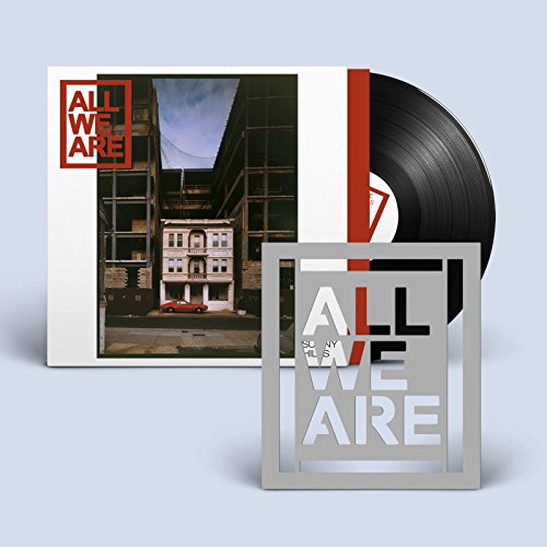 "Vinyl record and cover with 'All We Are' artwork, accompanied by a metal decorative sign."