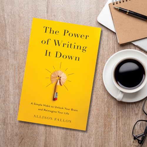 Yellow book titled "The Power of Writing It Down" with coffee and pen.