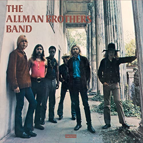 The Allman Brothers Band members posing in front of a building with stone columns.