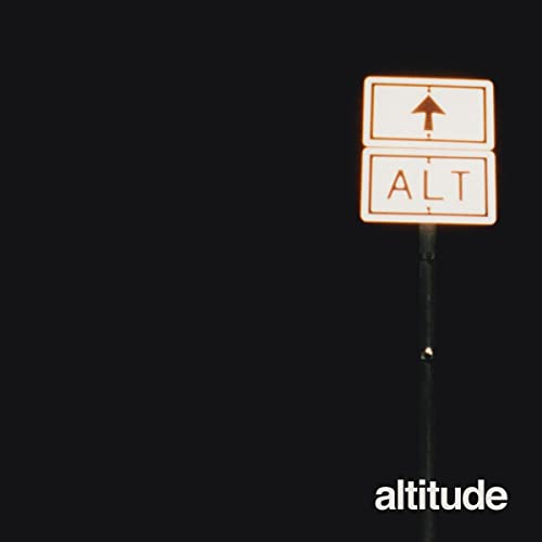 A road sign reading ALT with an upward arrow against a dark night background.
