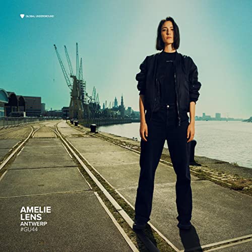 Amelie Lens portrait with industrial landscape and railway tracks background.