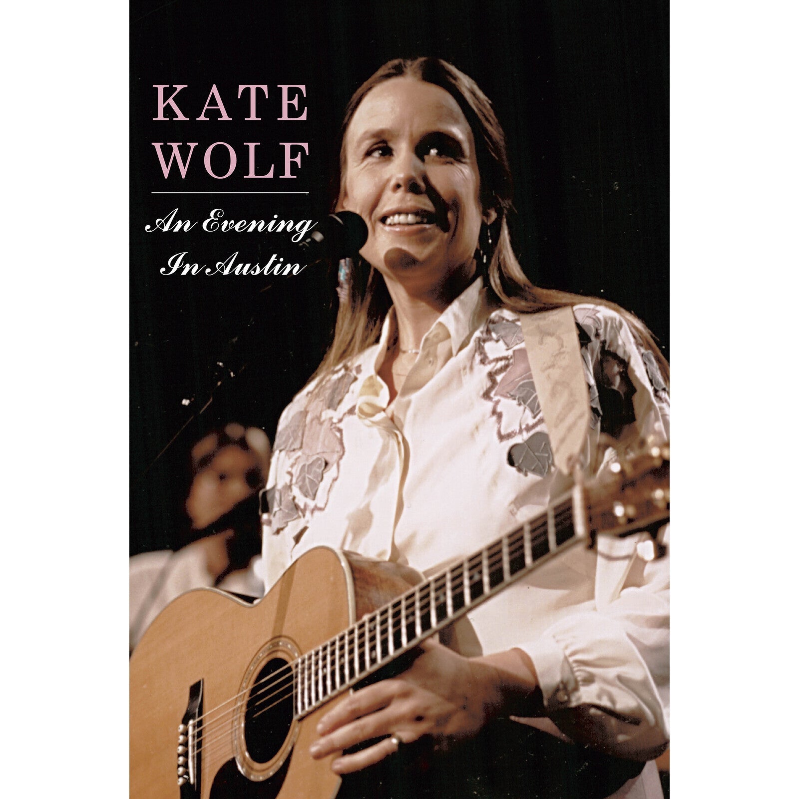 Kate Wolf on DVD cover, playing acoustic guitar onstage.