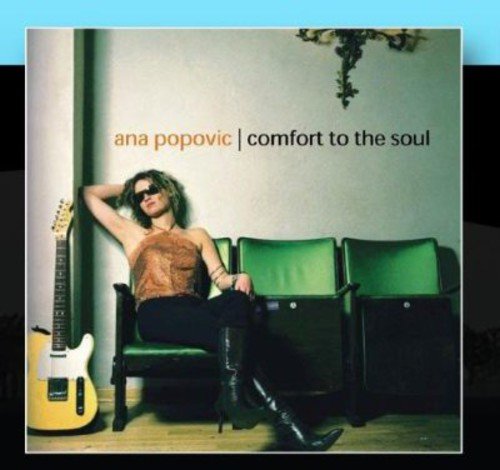 "Ana Popovic sitting on a green chair with a guitar beside her."