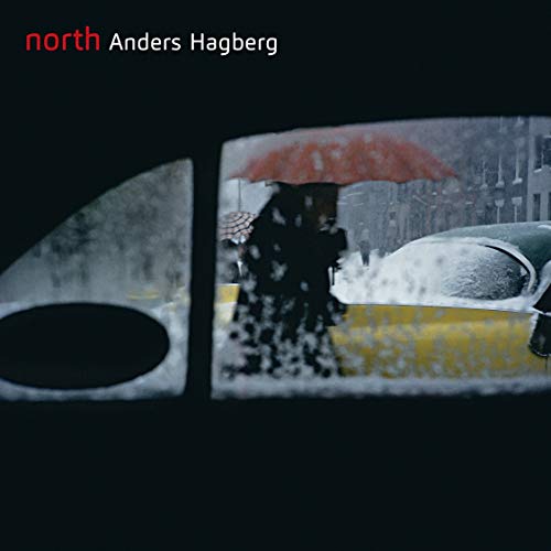 View through a car window of a person with a red umbrella in snow.
