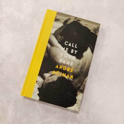 Call Me By Your Name book cover featuring two men lying together on sand.