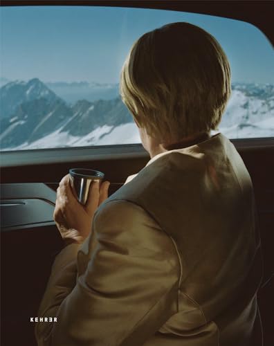Person with blonde hair looks at snowy mountains from a vehicle.