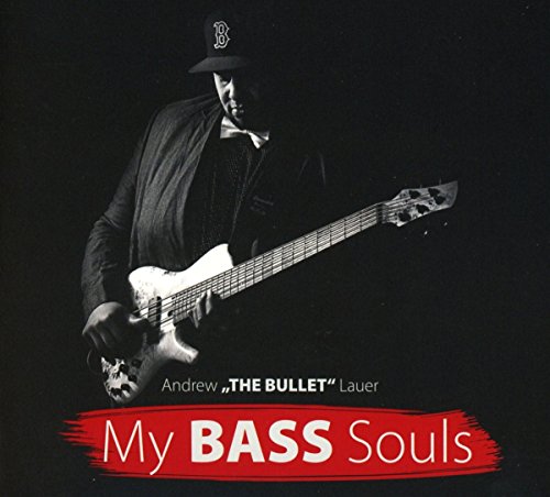 A man in a baseball cap playing a bass guitar against a black background.
