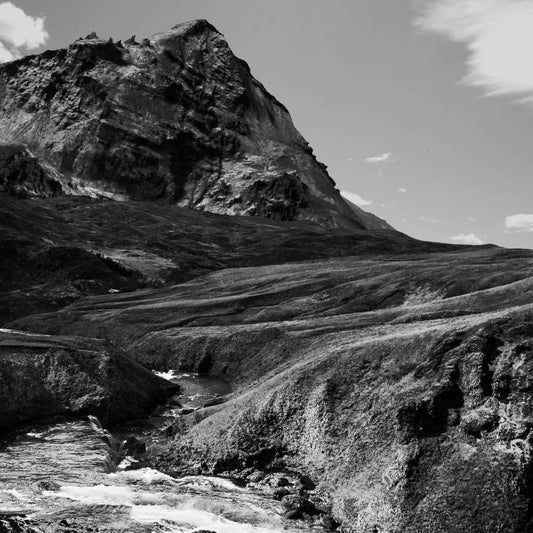 Black and white landscape of a mountain and flowing river.