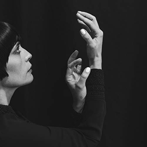 Black and white portrait of a woman with raised hands.