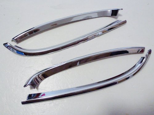Four shiny, curved chrome trim pieces laid out on a white surface.