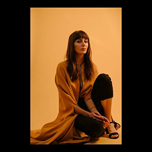 Anna Ash portrait, seated with a golden shawl against a warm background.