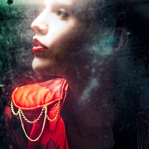 Profile view of Anna Calvi wearing a red garment with gold chain shoulder detail.