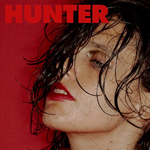 Close-up of Anna Calvi with wet hair, red lips, against a red background.