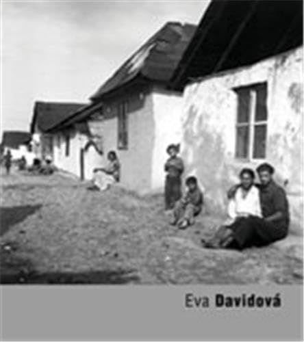 Black and white photo of a group seated outside a rural building.