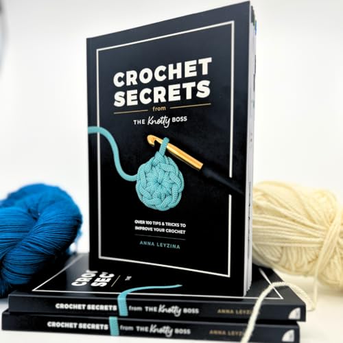 A stack of Crochet Secrets books with blue and cream yarn on a white background.