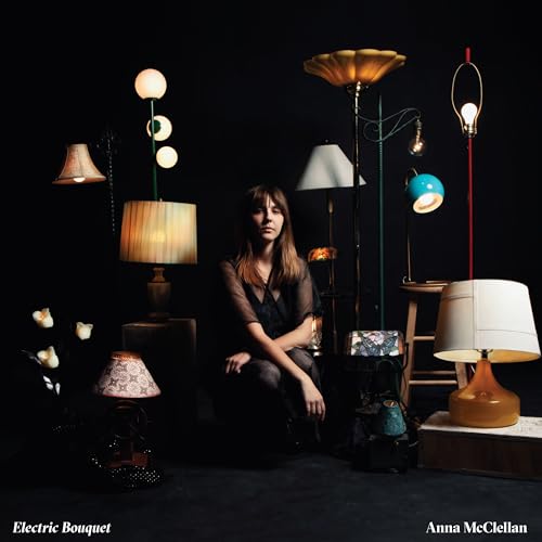 Woman surrounded by various vintage lamps in a dark room.