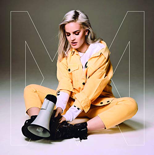 Anne-Marie sits on the floor wearing a yellow outfit and holding a megaphone.