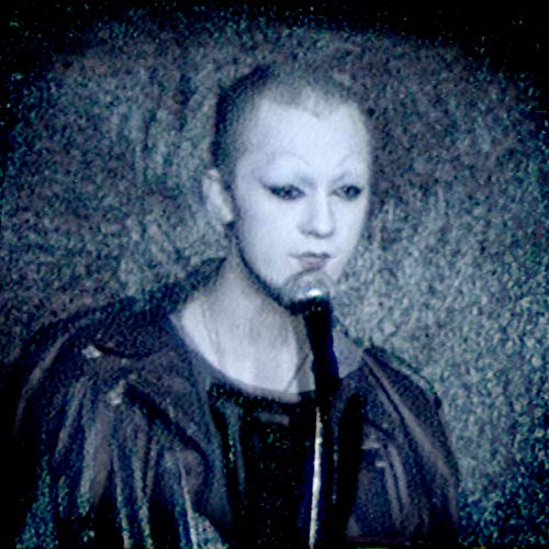 Close-up portrait of Anohni with dark makeup and a textured background.