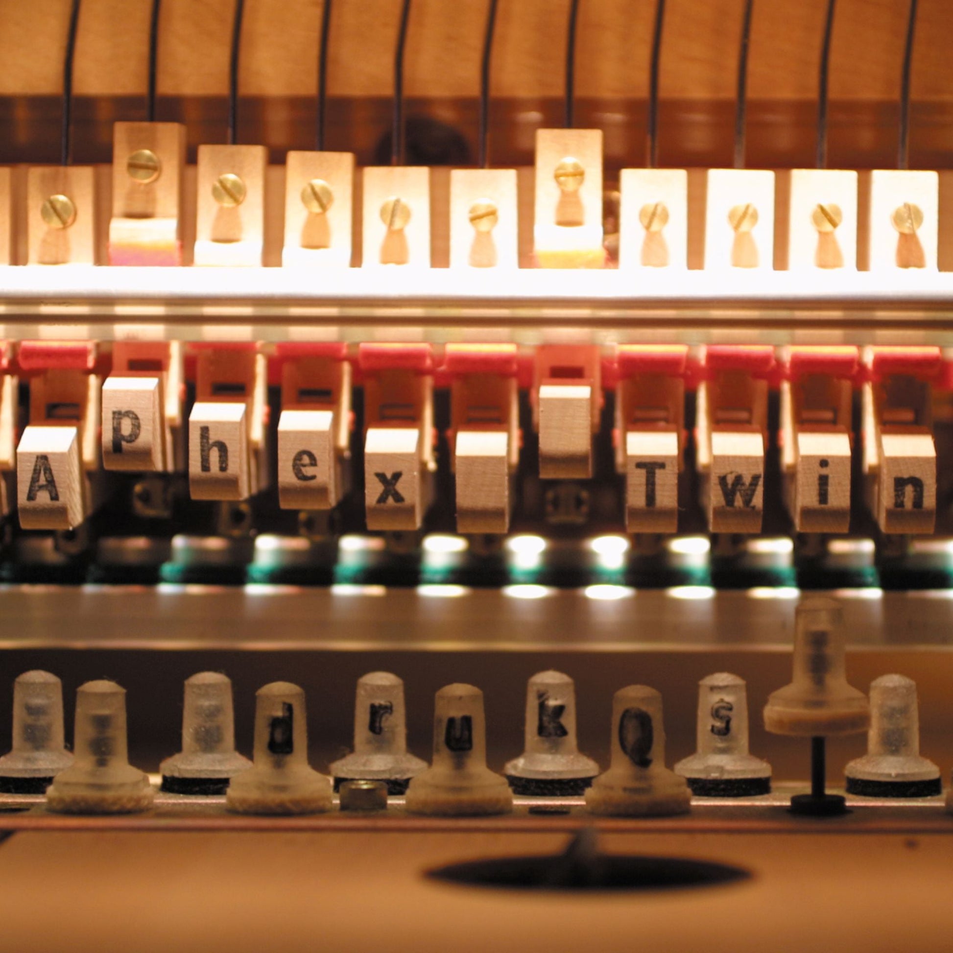 Close-up of a vintage letterpress displaying the album title "Aphex Twin Drukqs".