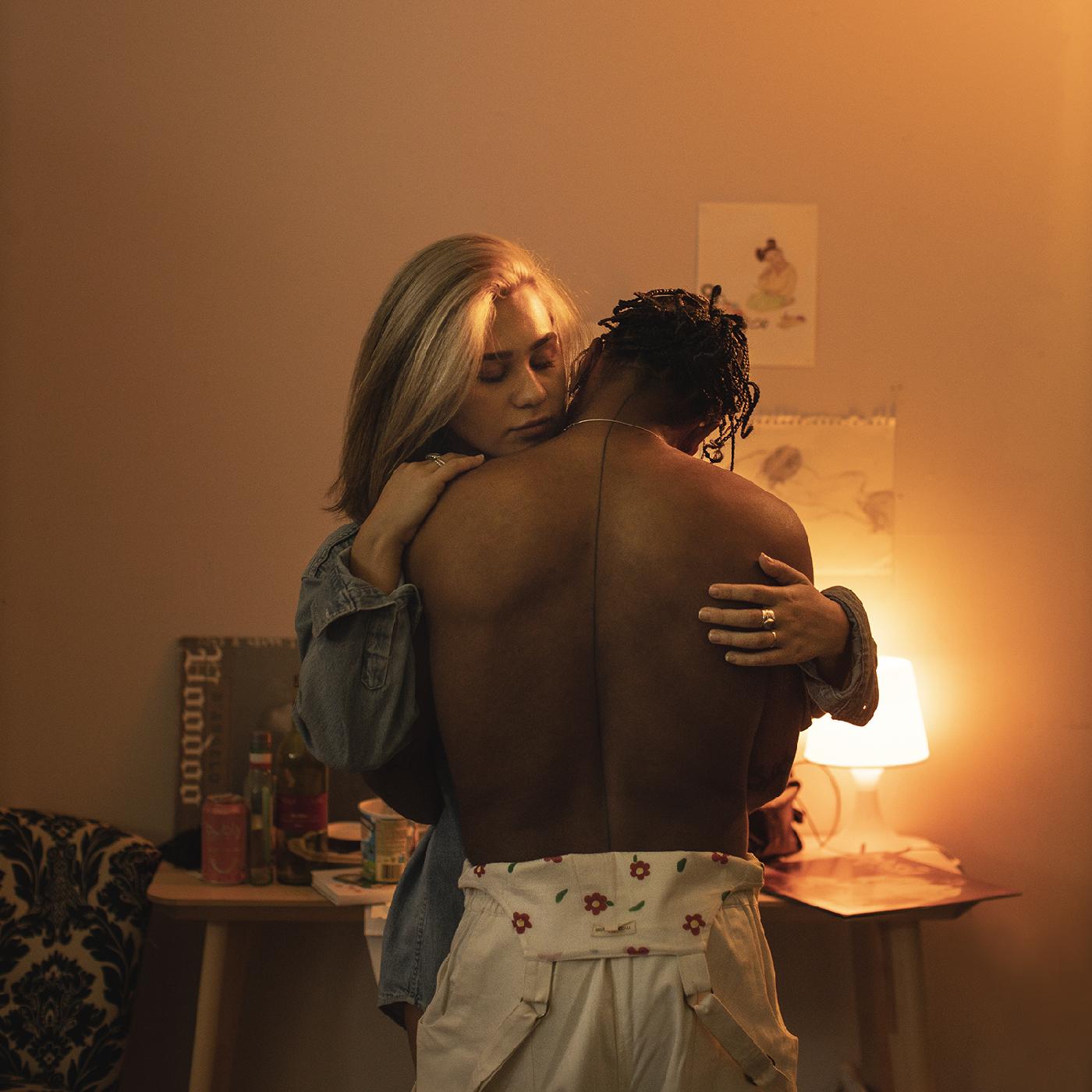 Couple embracing warmly in a dimly lit room, vinyl record visible.