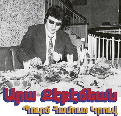 Black and white photo of a man at a table laden with food.