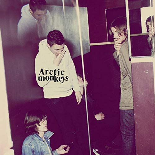 Arctic Monkeys album cover, "Humbug," featuring band members in a dimly lit room.