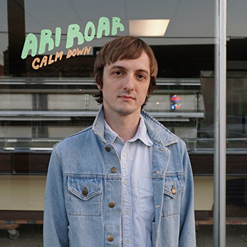 A man in a denim jacket stands before a storefront with album text overlaid.