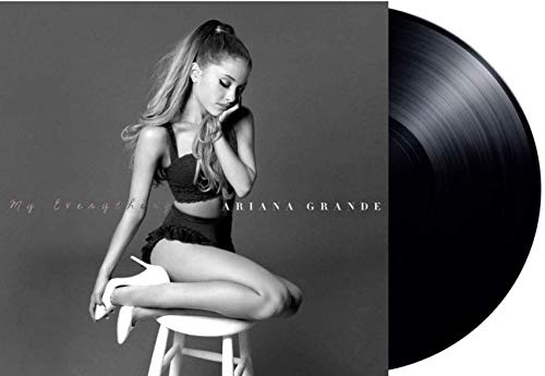 Ariana Grande sitting on a stool next to a black vinyl record.
